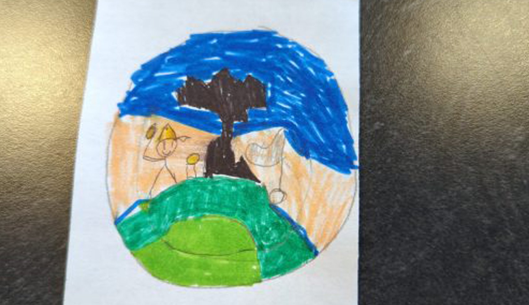 A child's drawing inside an oval, showing a dark silhouetted tree on a green golf mound with a flag, against an orange and blue sky backdrop. A stick figure golfer is visible.