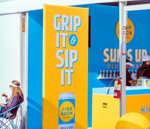 A brightly colored yellow and blue sign at an event plaza that reads,