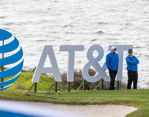Two golf course volunteers in blue jackets stand next to the large white