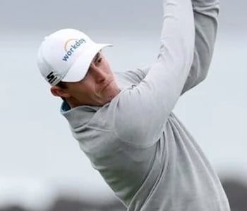 A close-up of golfer Matthew Fitzpatrick mid-swing, wearing a light gray pullover and a white Workday cap.