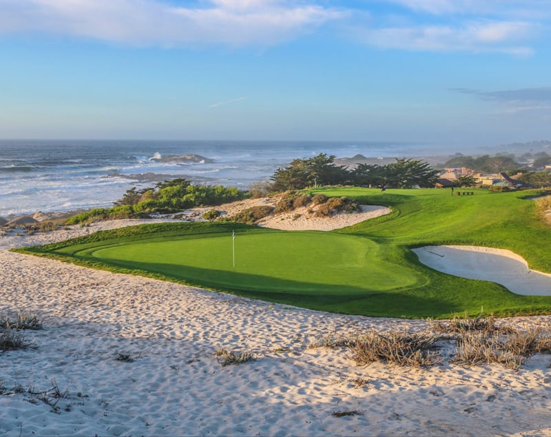 A beautiful view of a coastal golf green at Spyglass Hill, set right next to the white sand and the crashing waves of the Pacific Ocean.